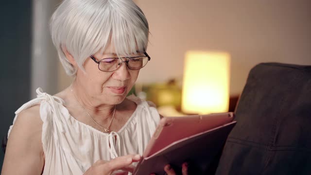 高级妇女在家里用数字平板电脑学习。奶奶在和家人开电话会议视频素材
