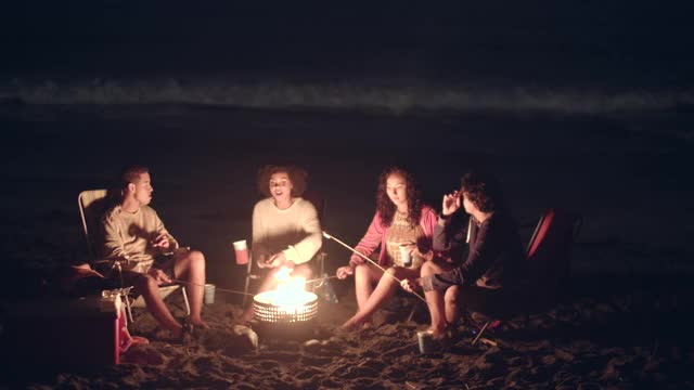 朋友们在晚上围着篝火玩视频下载