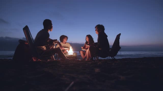 朋友们晚上在海滩上享受篝火视频下载