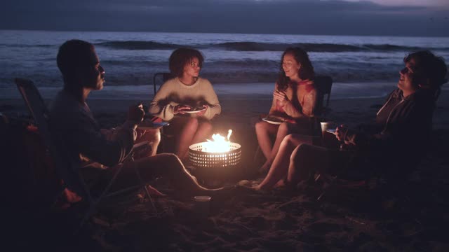 朋友们晚上在海滩上享受篝火视频购买