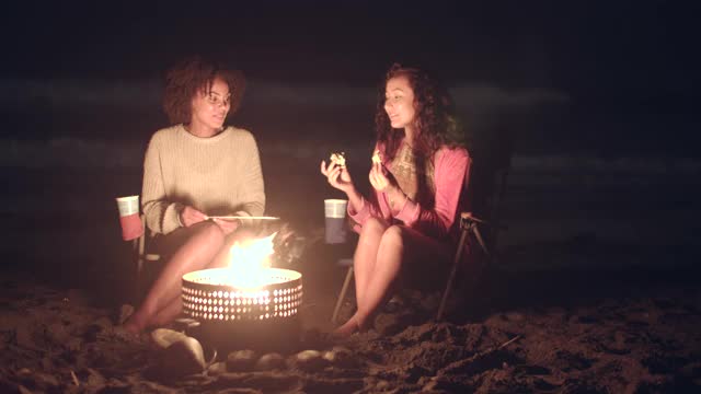朋友们在晚上围着篝火玩视频下载