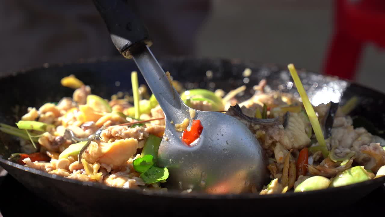 在餐馆里用平底锅煸炒香辣鱼肉，把切成薄片的鱼和蔬菜香草混合在一起视频素材