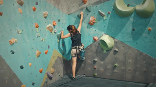 女孩在攀岩馆里攀岩，慢动作视频下载