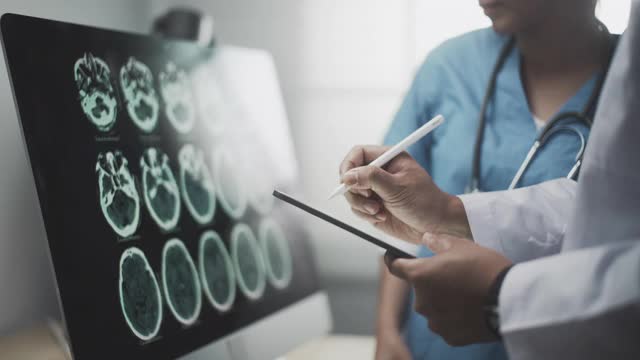 近距离手2医生看着大脑扫描显示在一个数字平板电脑上视频下载