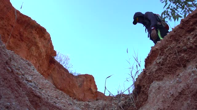 徒步旅行者从岩石上跳下来视频素材