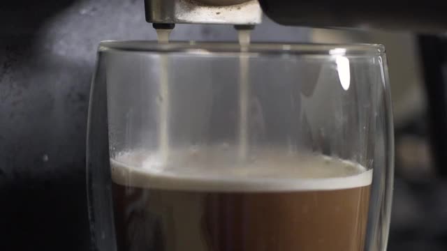 杯子里的咖啡从浓缩咖啡机滴下来，特写视频素材