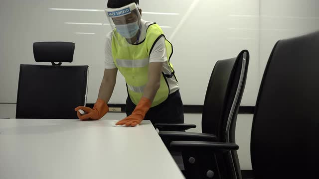 冠状病毒COVID-19预防清洁人员在公共会议室把手表面用杀菌消毒液擦拭清洁桌子。视频下载