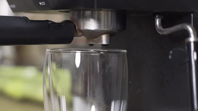 特写镜头的浓缩咖啡机倒咖啡在玻璃杯视频素材