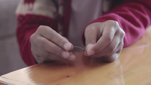 近距离的亚洲儿童女孩的手是线程珠串在家里的意图。孩子创造手工手镯，以发展手的能动性。视频下载