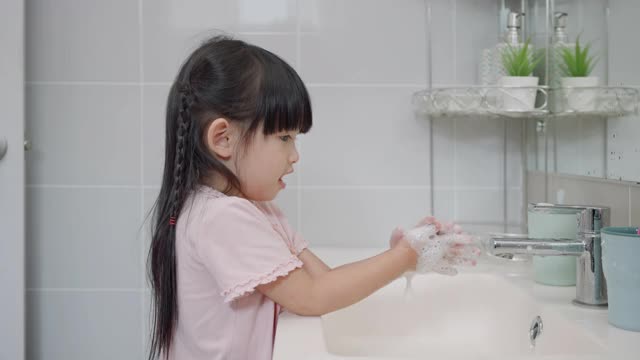 亚洲小女孩在厕所用肥皂和水洗手，以保持卫生和预防病毒感染。视频素材
