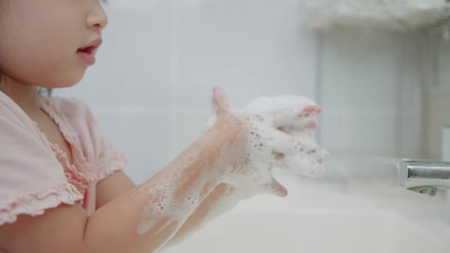 亚洲小女孩在厕所用肥皂和水洗手，以保持卫生和预防病毒感染。视频素材
