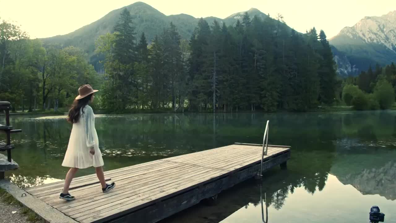 慢镜头:年轻女子沿着湖上的木码头走着视频素材