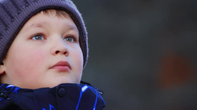 一个快乐的男孩的肖像，穿着夹克和帽子，看向一边。视频下载