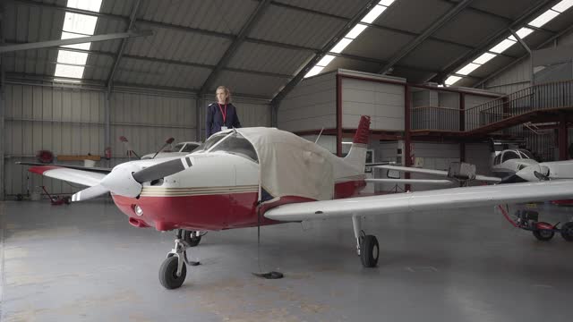 年轻女飞行员在机库发现一架装有防护罩的轻型飞机。视频下载