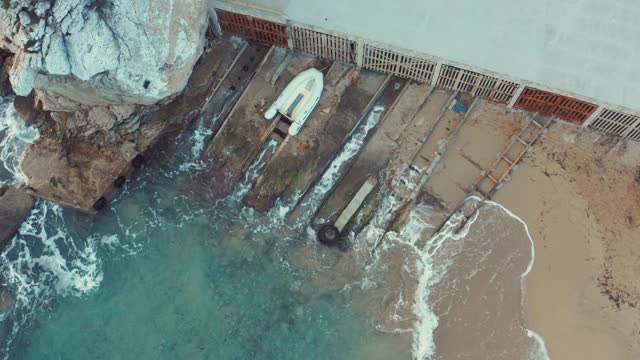 壮观的海滩鸟瞰图与传统的船庇护所和一艘船。4 k视频下载