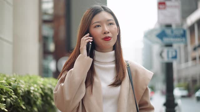 亚洲女人在城市里一边走路一边打电话视频素材
