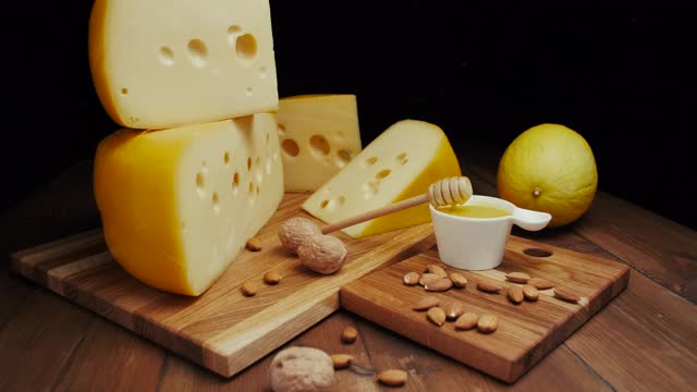 中等硬度的奶酪头，伊达豪达干酪放在木板上，加坚果和蜂蜜。幻灯片拍摄视频下载