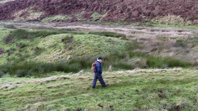 这是一名活跃的老年人在苏格兰西南部偏远乡村散步时的无人机跟踪镜头视频下载
