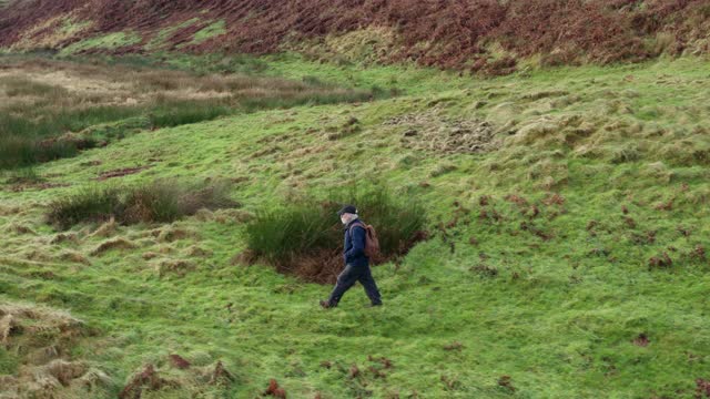 高角度的一个活跃的老人走在粗糙的荒地在苏格兰西南部偏远的农村位置视频下载
