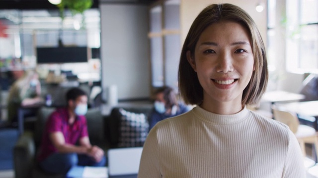 亚洲女商人的肖像看着照相机微笑在现代办公室视频下载