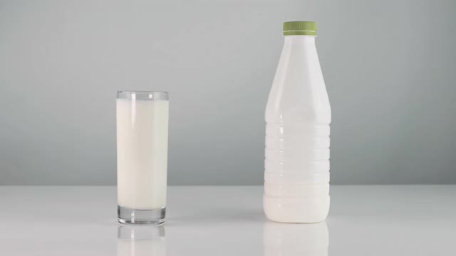 白色背景上的一杯牛奶。酸乳酒白色的酸奶。这家伙伸出手指喝健康的开菲尔一杯酸奶的特写。牛奶产品。视频素材