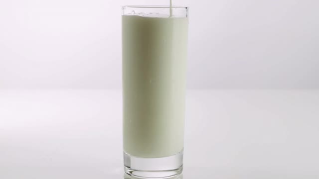 开菲尔的流动方向相反。加牛奶效果很好。牛奶在杯子里。一股酸奶。在白色的背景上。视频素材