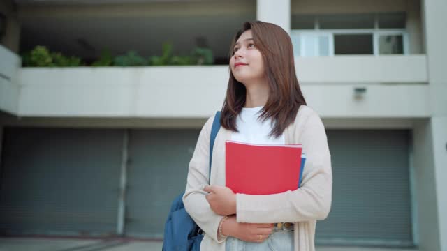亚洲女大学生背着背包，站在学校走廊在校园里。视频素材