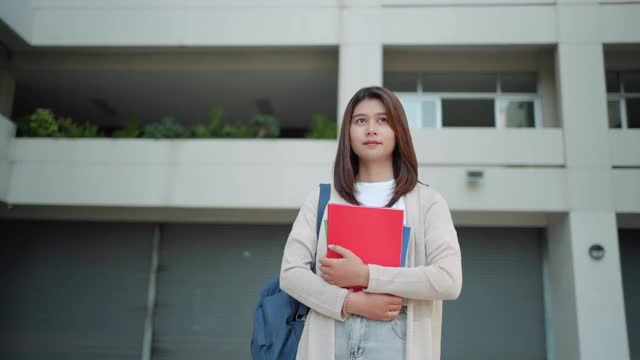亚洲女大学生背着背包，站在学校走廊在校园里。视频素材