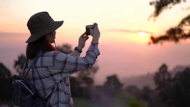 女旅行者在山上一个美丽的地方拍摄日落视频素材