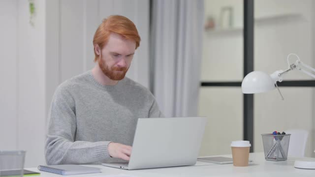 胡子红发男子在笔记本电脑上打字时背痛视频素材