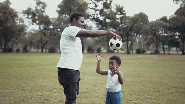 快乐的爸爸和儿子在公园里踢足球视频素材