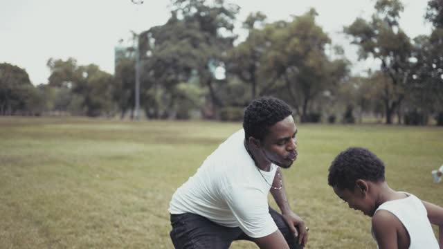 快乐的爸爸和儿子在公园里踢足球视频素材