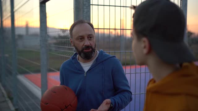 父亲和儿子在户外打篮球后谈话视频素材