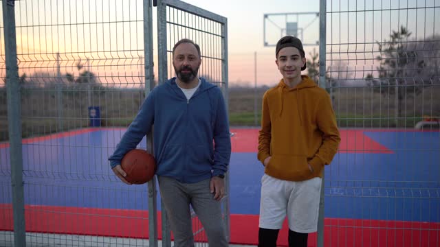 十几岁的男孩享受和他的父亲在篮球场上的时间视频素材