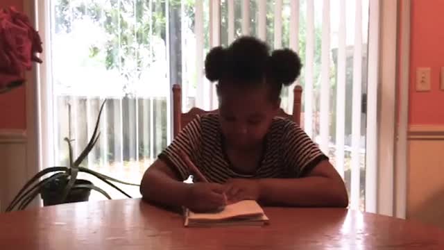 一个可爱的小学小女孩在网上上课时记笔记、听课视频素材
