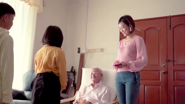 亚洲华人爷爷在家给孙子孙女发红包。快乐带着笑脸。视频素材