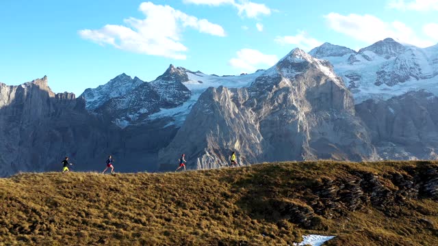 无人机拍摄的一组跑步者沿着山脉的边缘跑步，后面是山脉视频下载