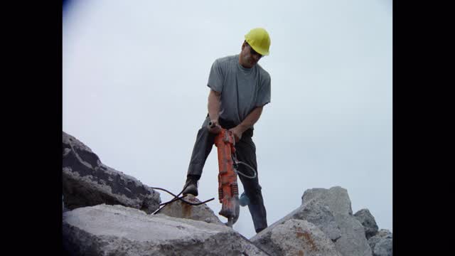建筑工人使用手提钻在建筑工地打破水泥的低角度视图视频下载