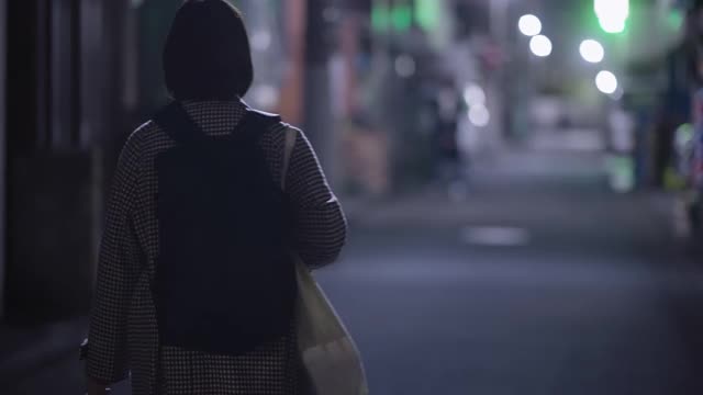 在冬天的晚上，年轻女子戴着防护面罩走在街上视频购买