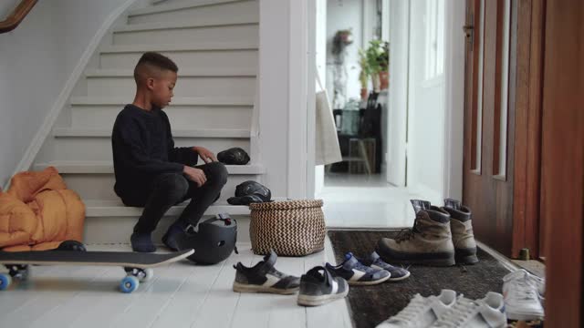 手持拍摄男孩戴着护膝坐在家门口的台阶上视频下载