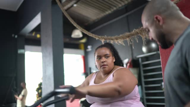 健身教练在健身房帮助一位年轻女士锻炼视频下载