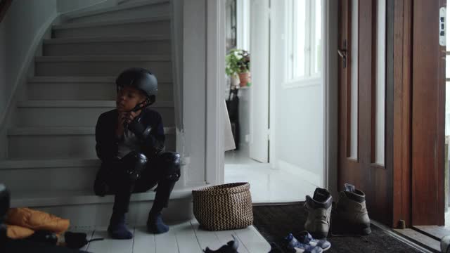 手持拍摄的男孩戴着运动头盔，而坐在家门口的台阶上视频素材