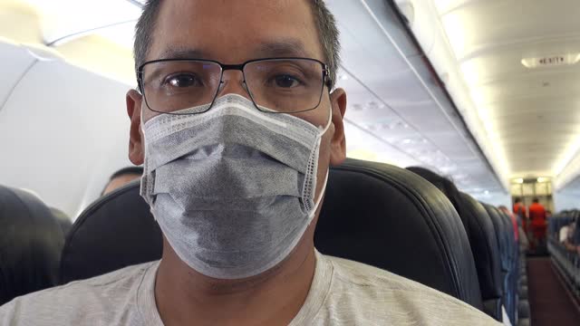 亚洲男子在飞机上戴面具视频素材