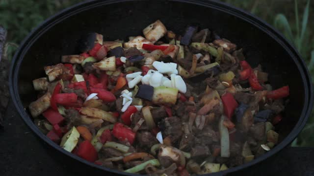 把茄子和肉、洋葱、胡萝卜、西葫芦一起放在一个大锅里。所有的原料都要用木铲混合。在明火上做饭视频下载