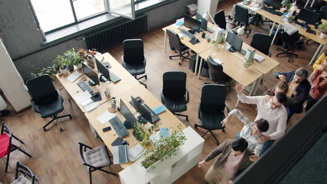 高角度的欢乐的人办公室工作人员跳舞在现代开放空间的工作场所视频素材