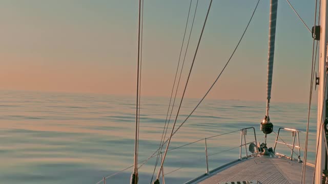 日落时分，在大西洋平静的海面上，帆船在平静的水面上低头。帆和钻机的视图视频下载