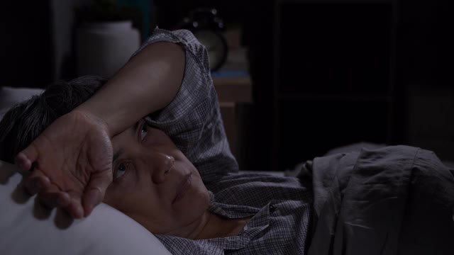 抑郁的老年妇女躺在床上无法入睡视频素材