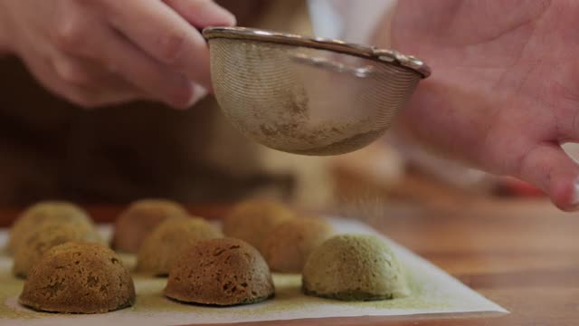 面包师在刚烤好的饼干上洒上绿茶粉。视频素材