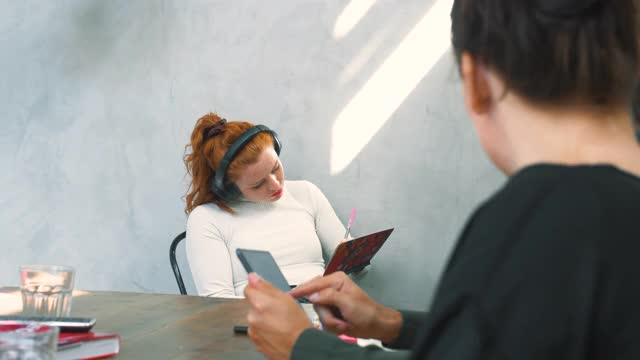 女企业家戴着耳机，在同事面前用平板电脑工作视频素材