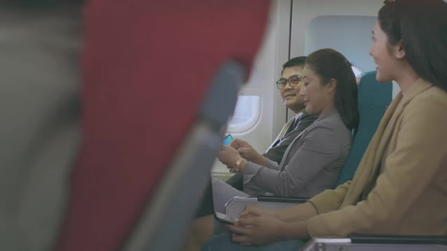 一名年轻女子在飞行中使用智能手机时大笑。视频素材
